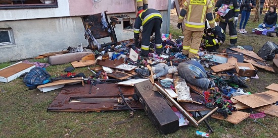 Częściowo wypalone, osmolone wyposażenie domu i zabawki wyrzucone na trawnik przed blokiem