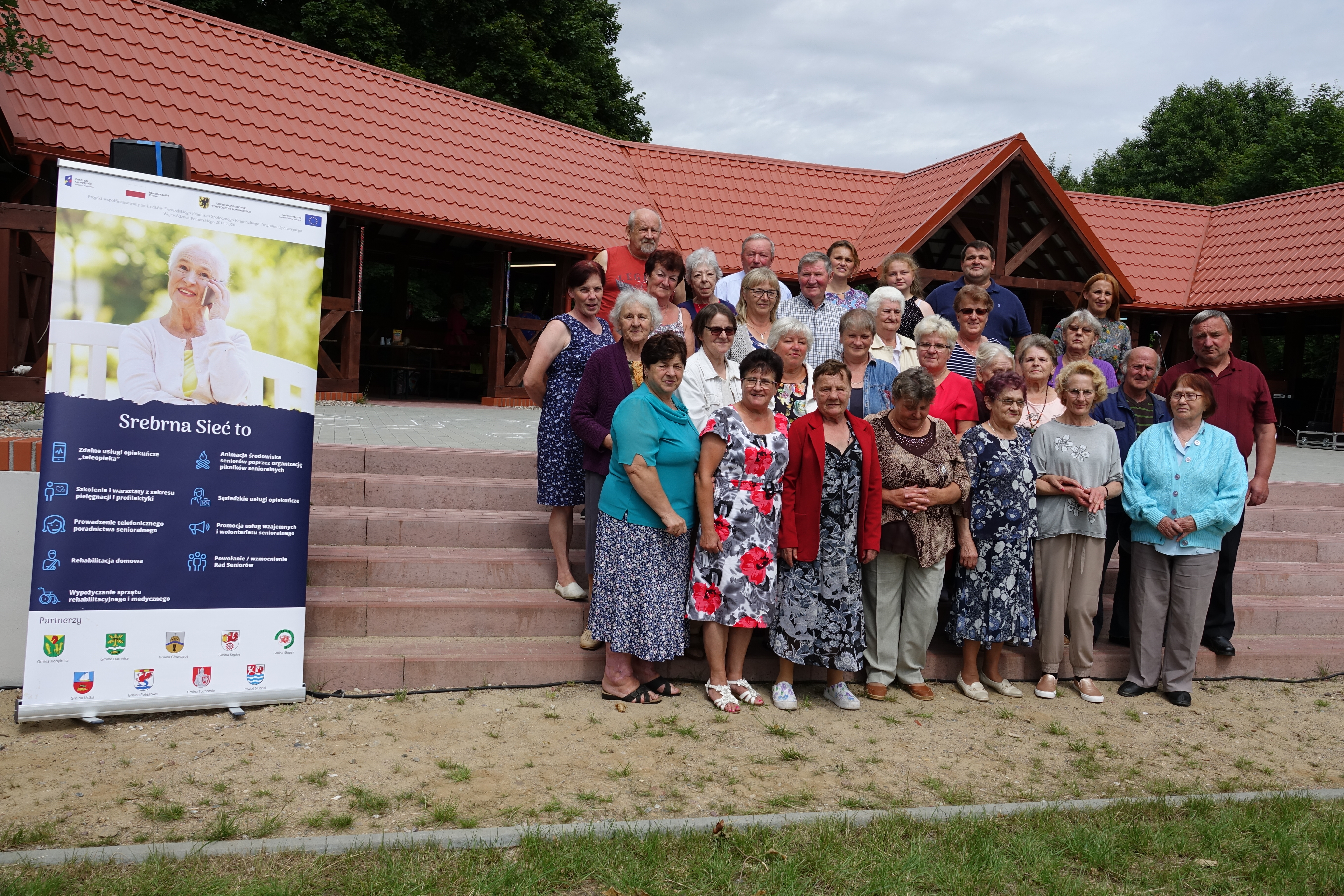 Grupa z gminy Główczyce pozująca do zdjęcia na tle obiektu w Strzyżynie, gdzie odbywała się biesiada.