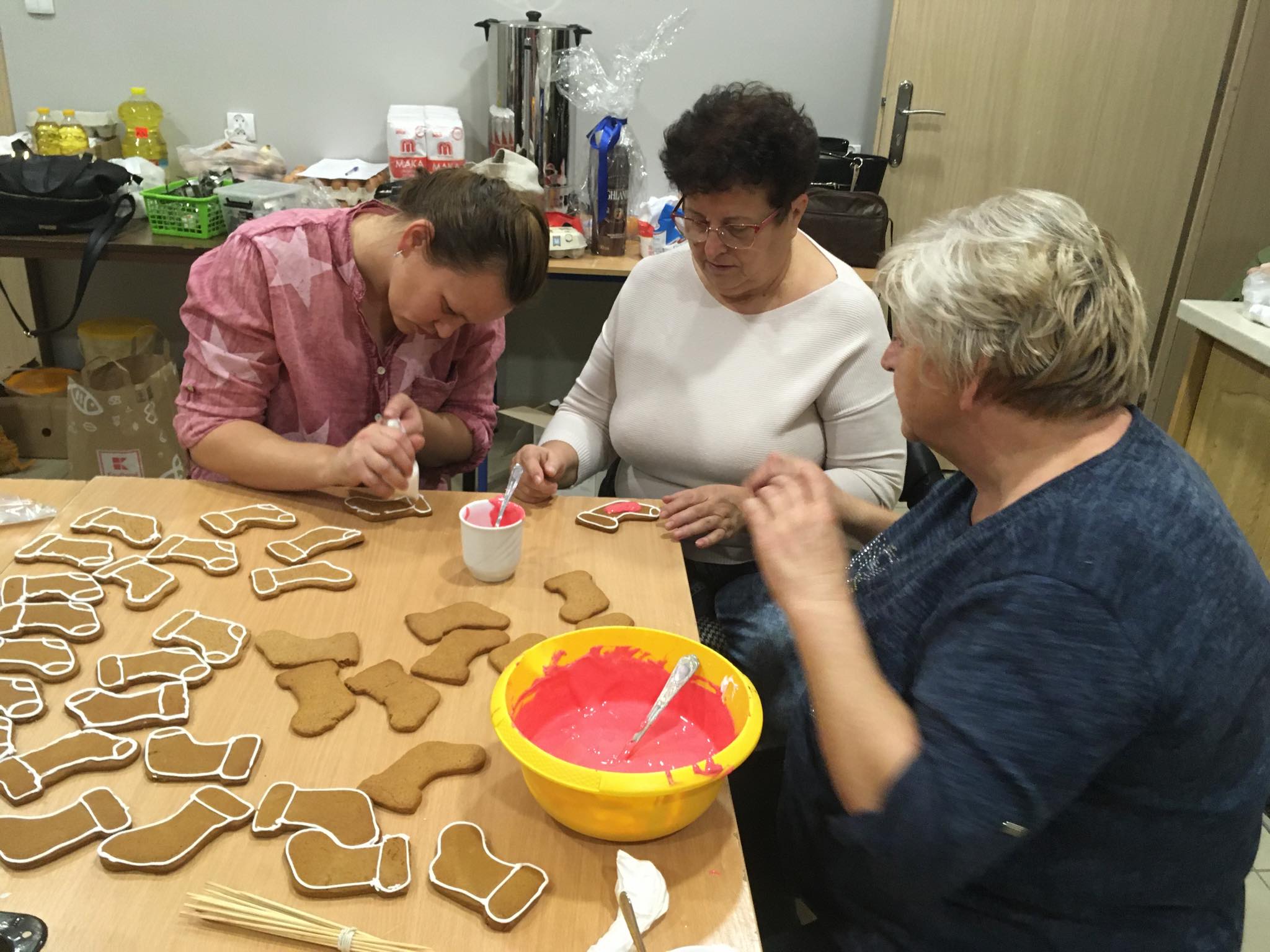 Wolontariusze i uczestniczki Kreatywnego Klubu Kobiet podczas wyrobu pierniczków w kuchni GOK.