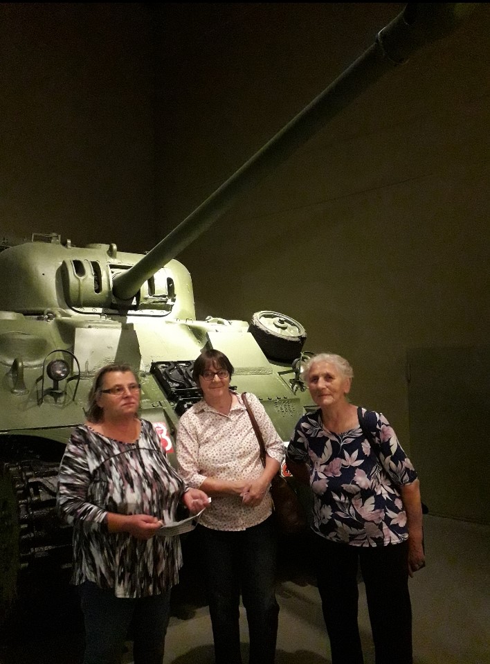 Trójka seniorek na tle czołgu w muzeum II wojny światowej