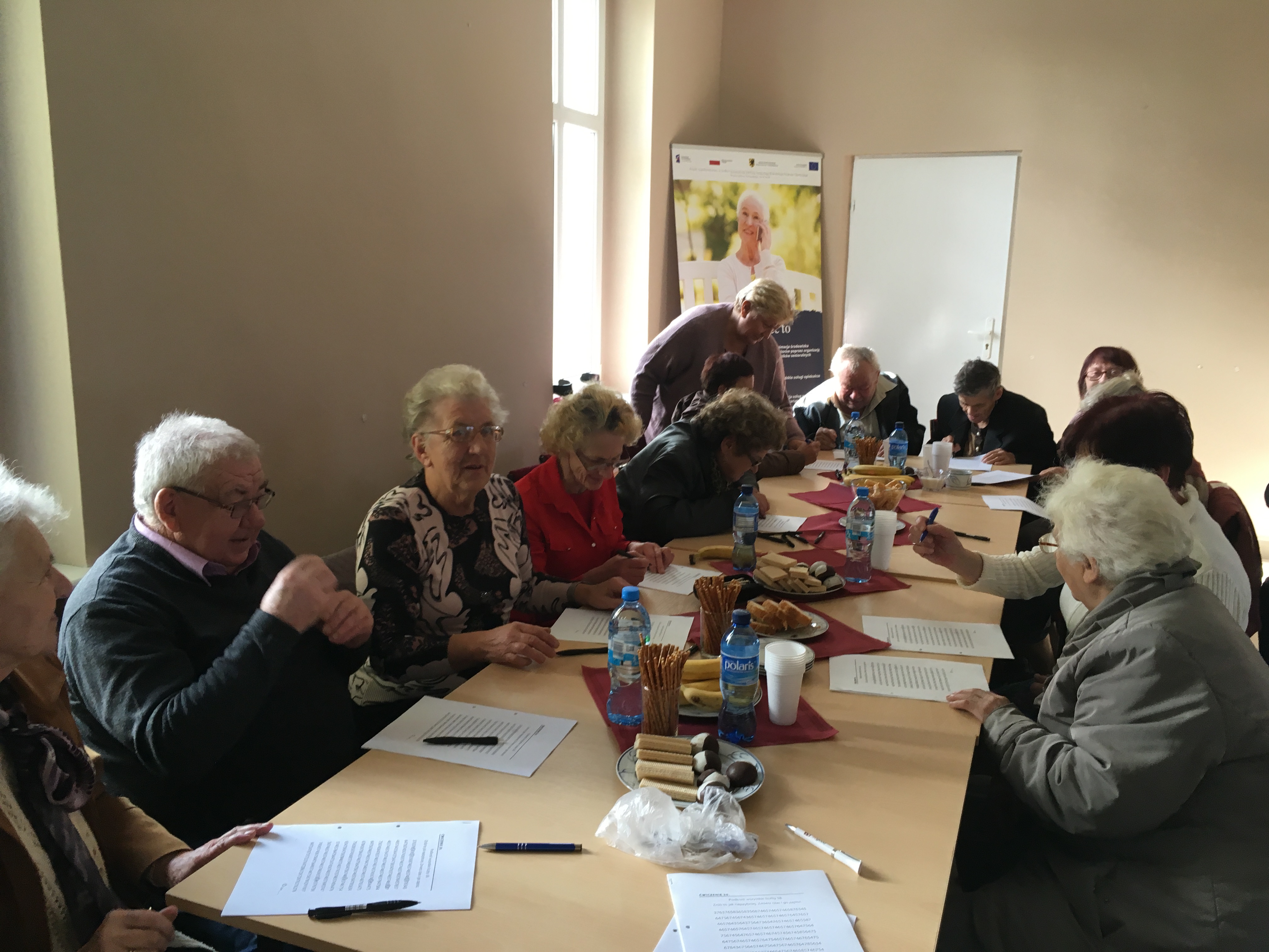 Seniorzy siedzący przy stole podczas organizowanego szkolenia w ramach projektu