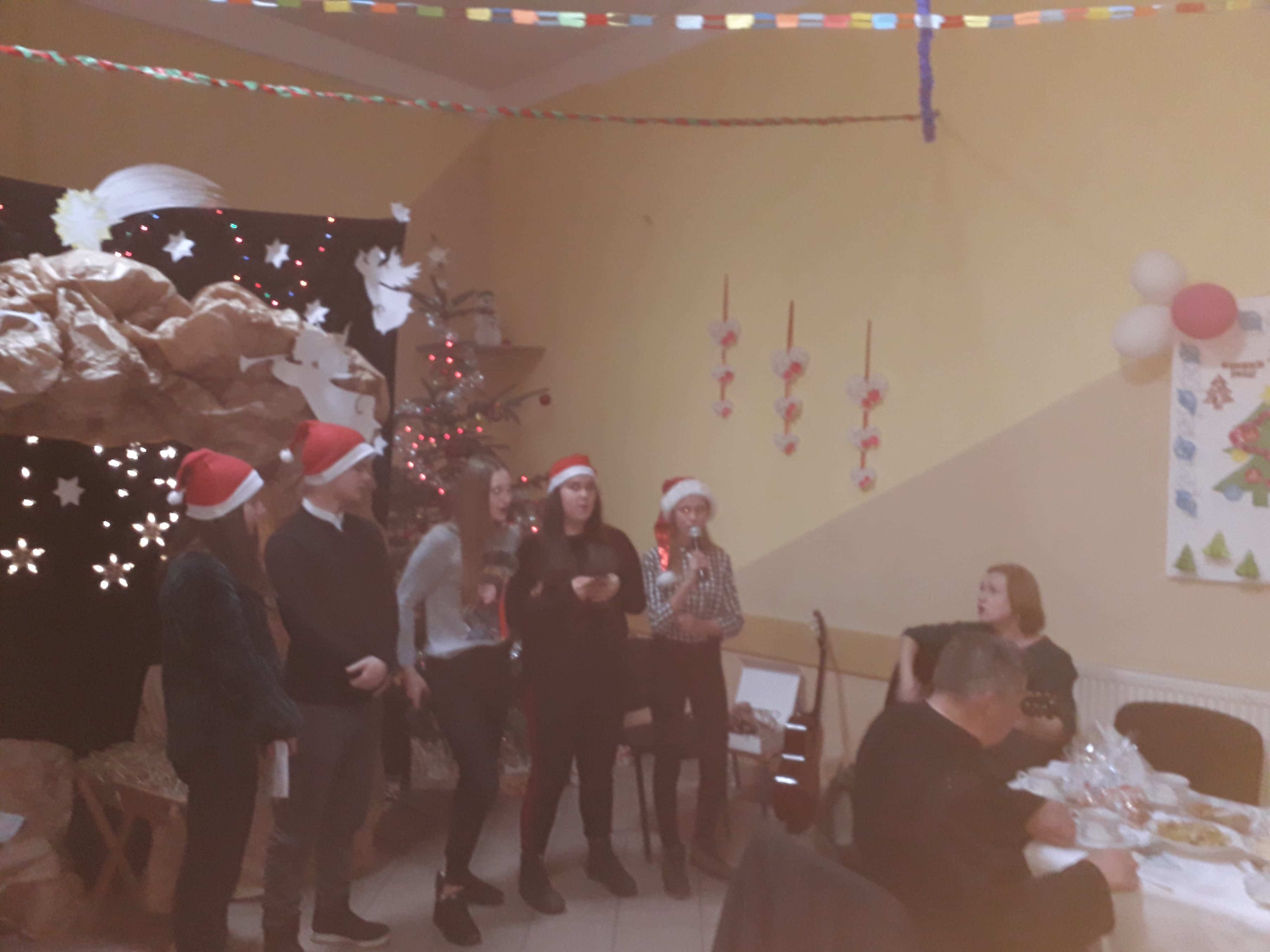 Wolontariusze śpiewający kolędy podczas spotkania wigilijnego