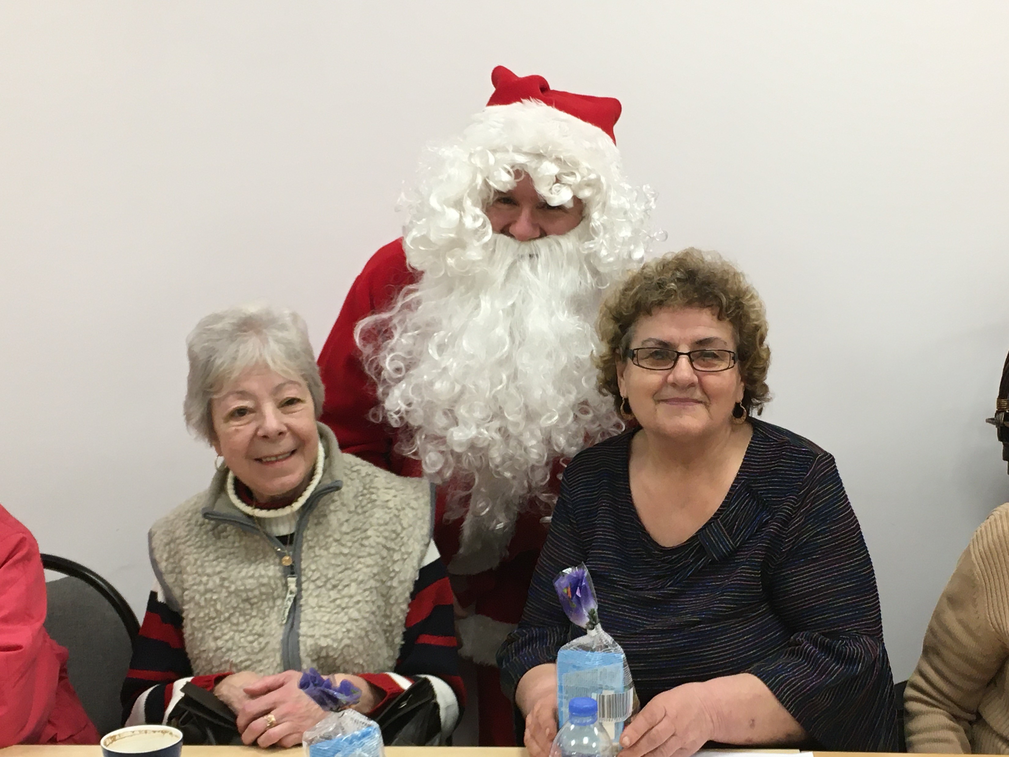 Mikołaj pozujący do zdjęcia wraz z dwójką seniorek uczestniczących w szkoleniu.