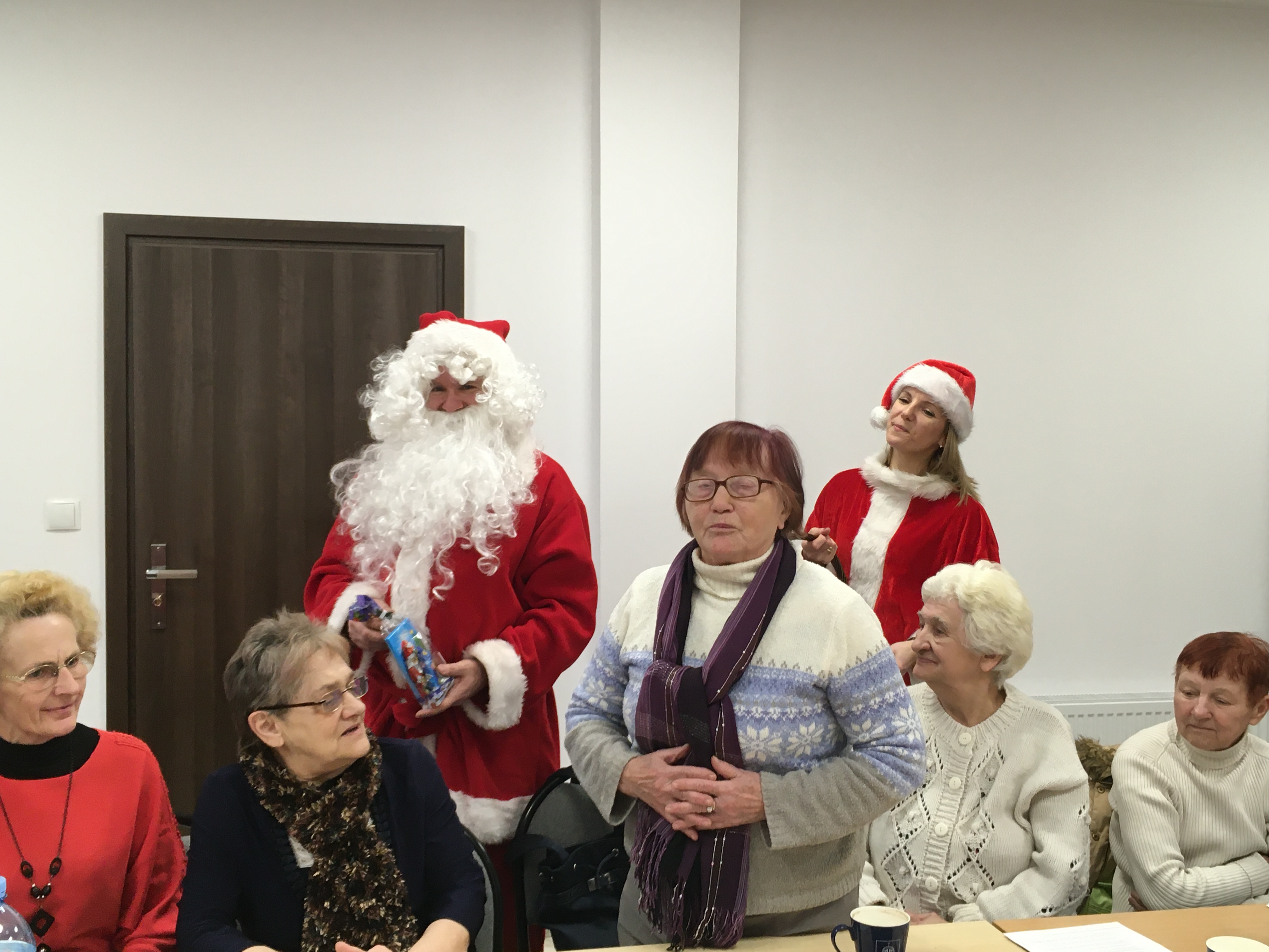 Święty Mikołaj wręczający słodycze seniorom.